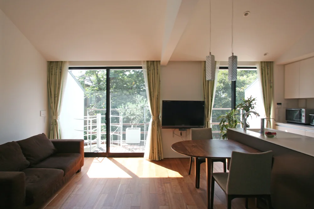 From the living room, the deck terrace offers borrowed views of the neighboring greenery.