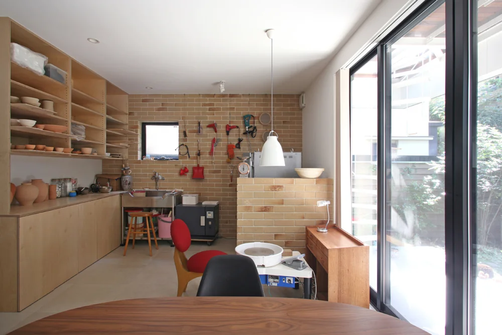 The front wall is finished with durable brick tiles, accommodating the electric kiln and a washbasin.
