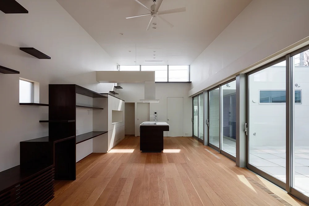The LDK receives natural light through high windows and features large floor-to-ceiling openings facing the modern courtyard.
