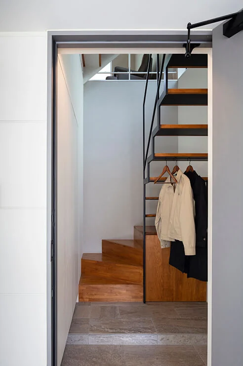 The staircase is constructed of steel, allowing natural light from the upper floors to penetrate through the landing area.｜Two-Generation Courtyard House on a Narrow Irregular Lot