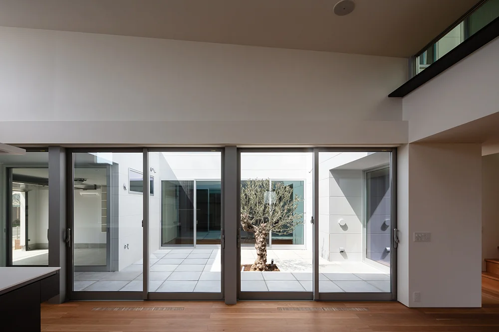 An ancient olive tree serves as a symbolic centerpiece in the courtyard, which connects the LDK and the garage through the courtyard space.