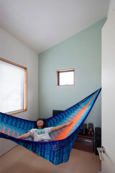 The third floor, elevated by one full story from the second, is the husband’s hobby room with a high ceiling and a hammock suspended within