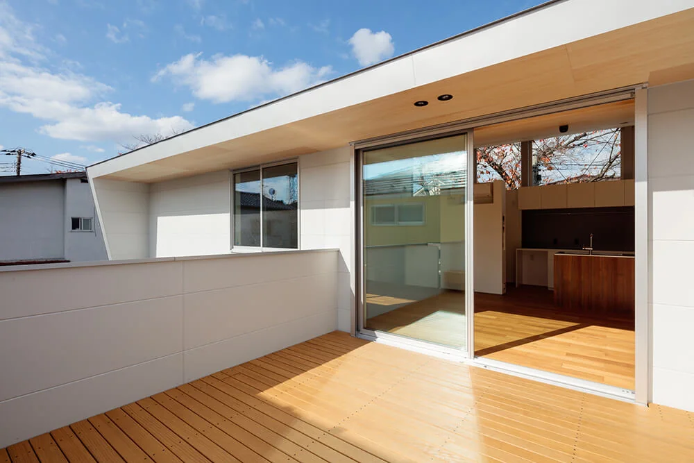 The south-facing sloped roof functions as an eave, shielding the terrace from rain and harsh summer sunlight; the soffit is clad with natural linden plywood.
