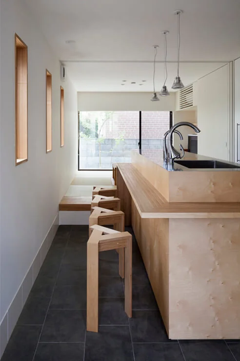 The kitchen counter is crafted from Russian birch laminated plywood, with a raised tatami alcove located beyond