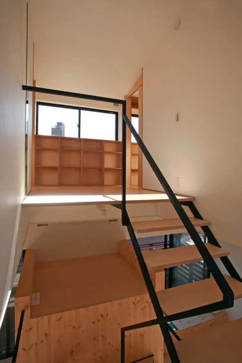 Half a story up, the hall divides into two children’s rooms for the sisters