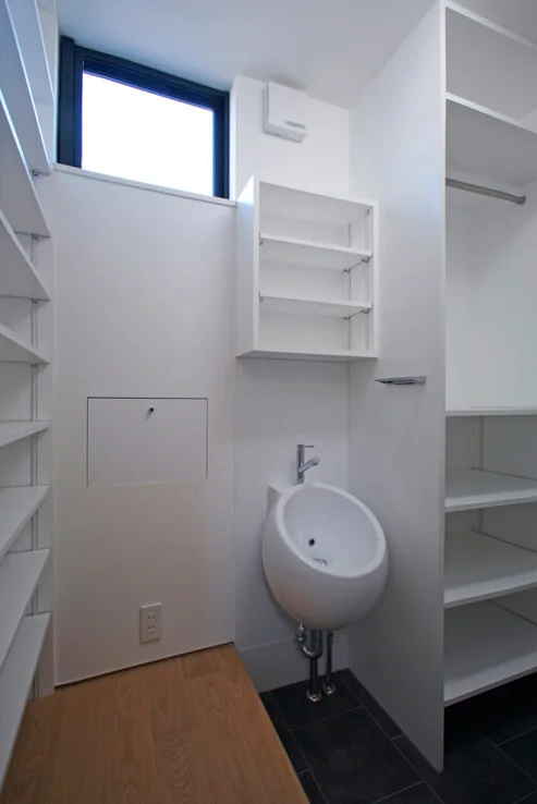 The shoe-in closet adjacent to the entrance incorporates custom shoe storage and a handwashing basin, with mail retrieval facilitated through a side door