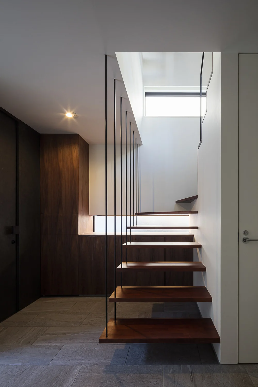 Entrance staircase appears light and suspended via tension rods, with built-in shoe storage directly ahead｜Residence Featuring an Indoor-Integrated Terrace