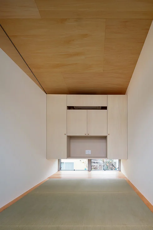The multipurpose Japanese-style room, suitable for overnight guests and cherry blossom viewing, features a low window framing a persimmon tree.