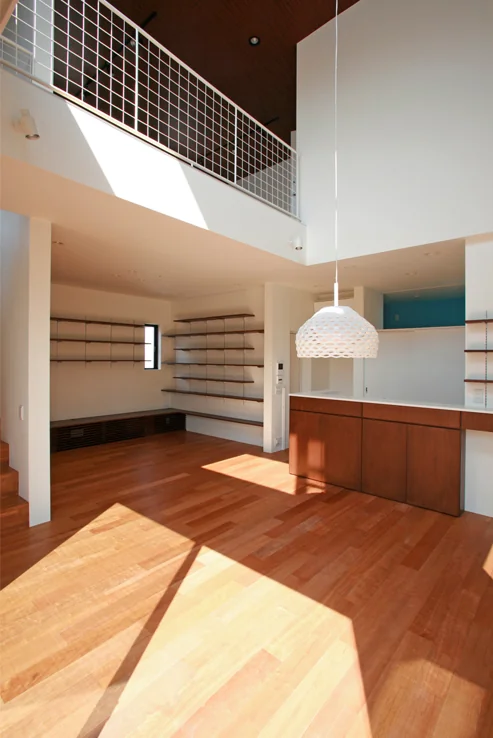 The dining area features a double-height space overlooking the living room, with the second-floor railing composed of wire mesh to prevent falls.