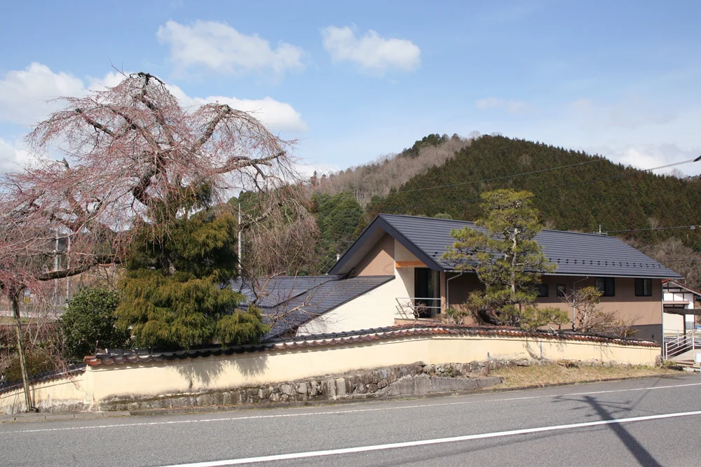 しだれ桜やなだらかな山並みと調和する佇まい