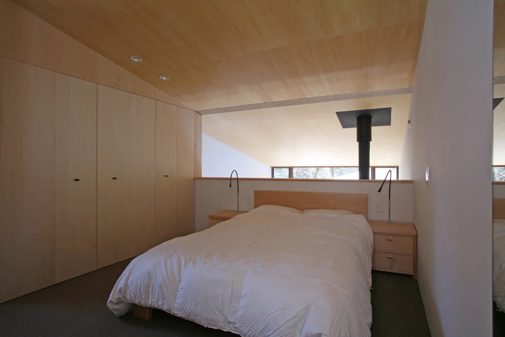 Master bedroom connected to the living room void; six sliding doors allow the space to be closed off when desired｜House Nestled Among the Trees