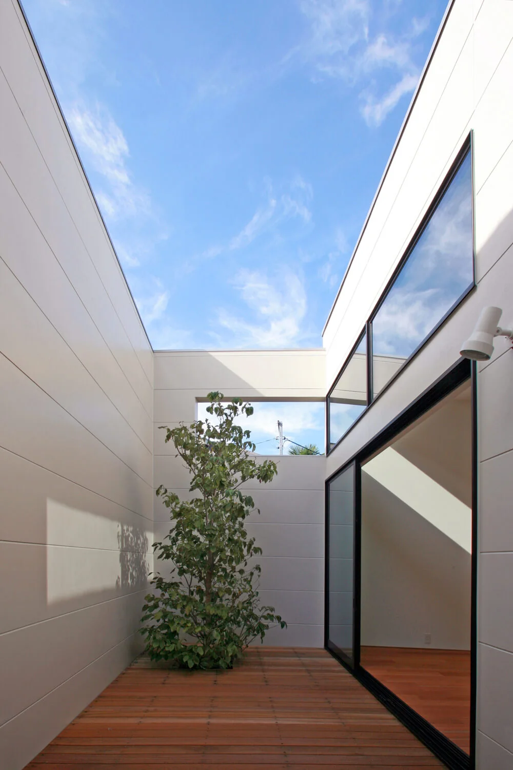 The terrace channels light and air into the interior; its 2.4-meter cantilevered balcony is excluded from the building area calculation.
