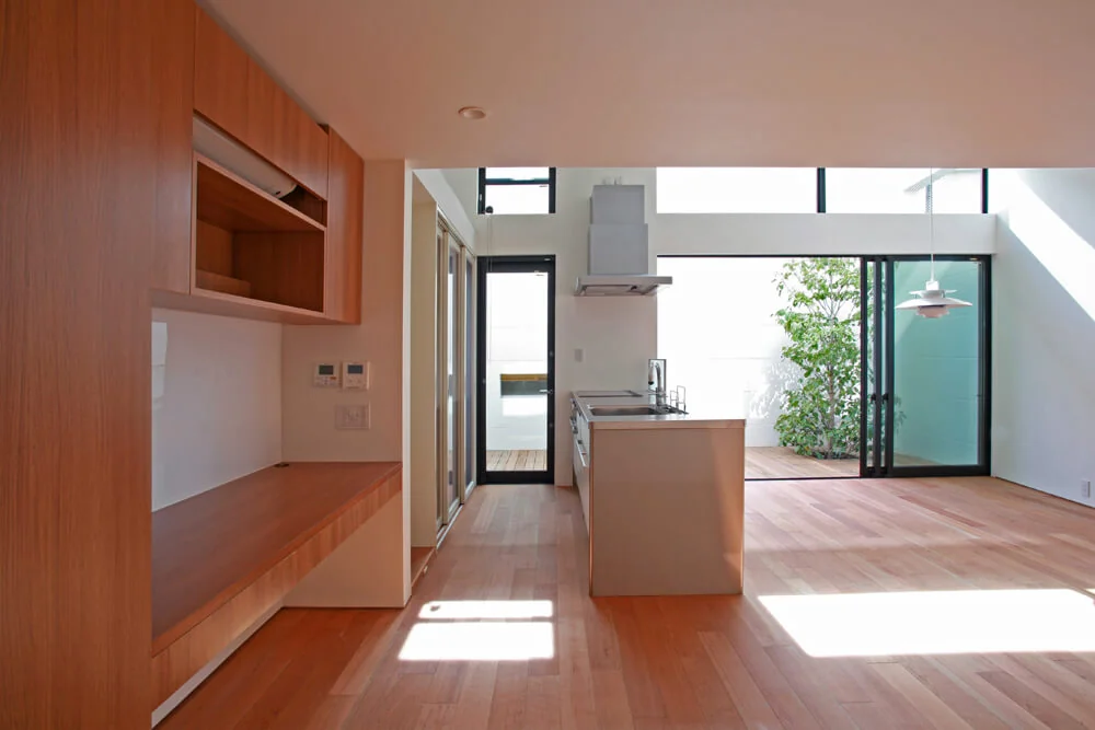 Winter sunlight streams through the high windows of the south-facing deck terrace with its elevated ceiling; a workspace is located to the left.