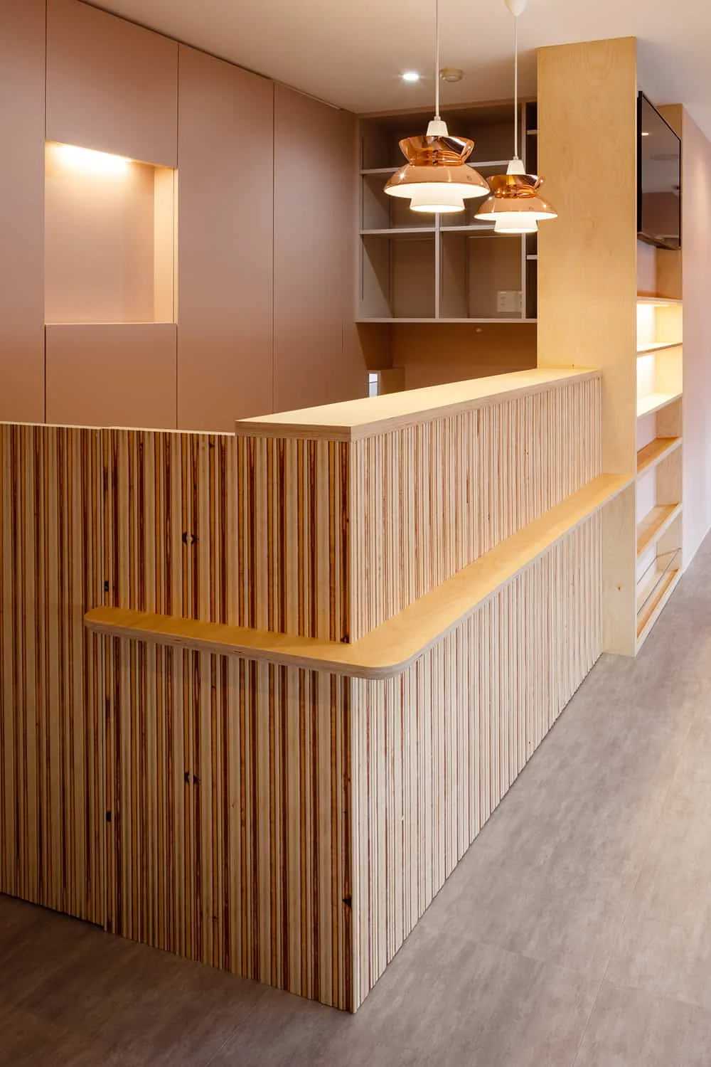 Reception counter combining Russian birch laminated plywood and a dado wall finished with Nagi texture.