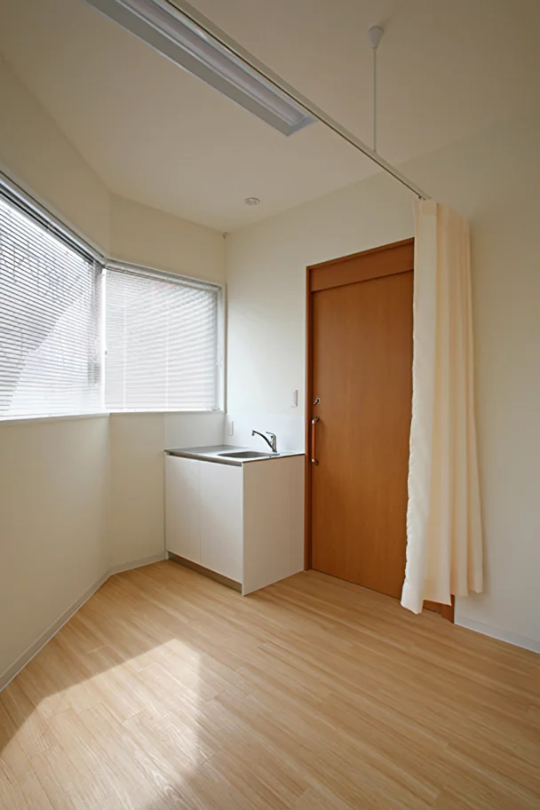 Treatment room with a sink; examination table positioned behind a curtain on the right side