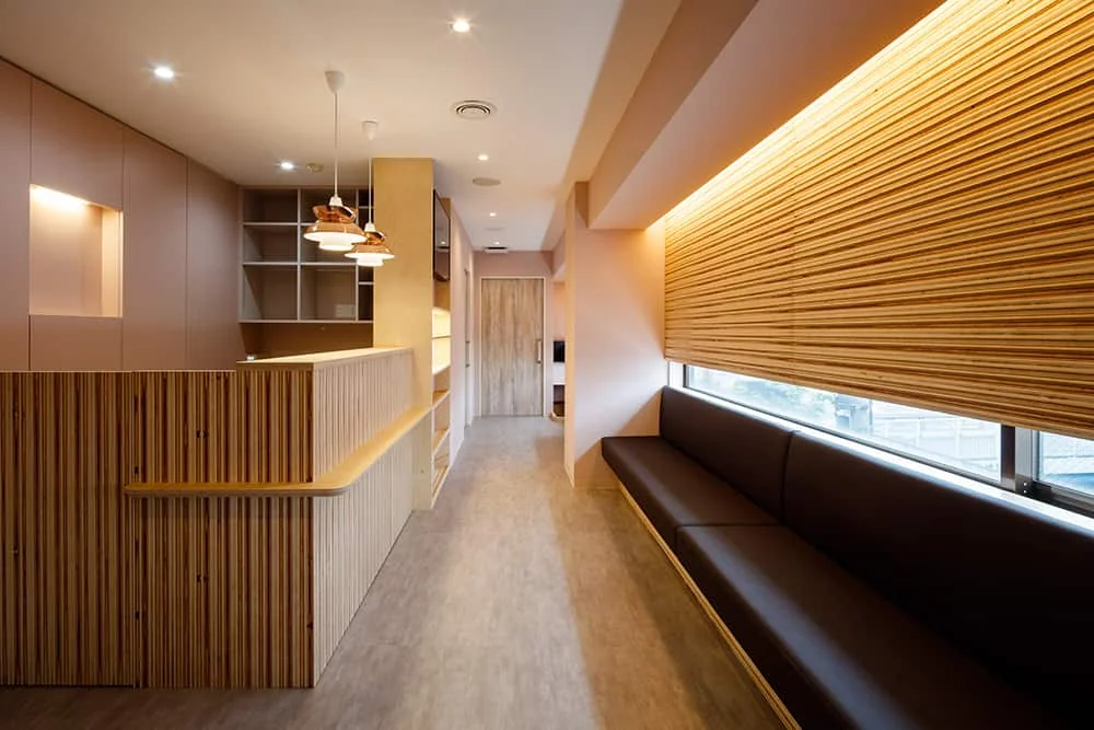 Reception and waiting area viewed from the entrance, featuring interior finishes with Russian birch laminated plywood panels treated with a Nagi (calm sea) texture.