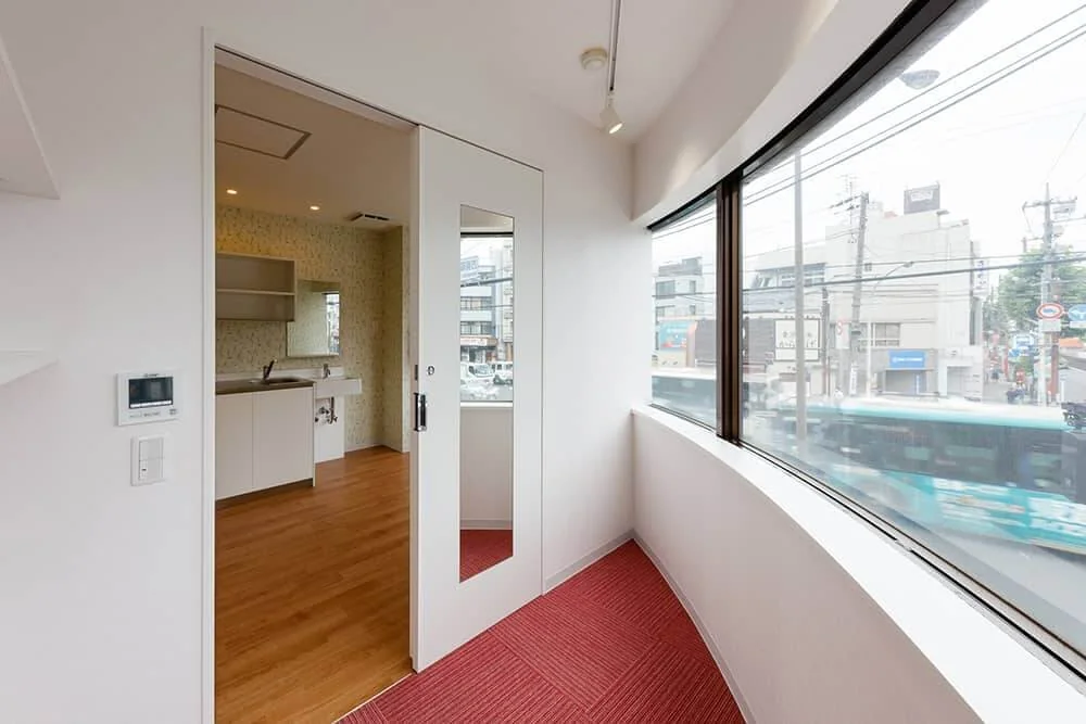 View from the director’s office toward the staff room, featuring a sliding door with a full-length mirror and carpeted flooring.