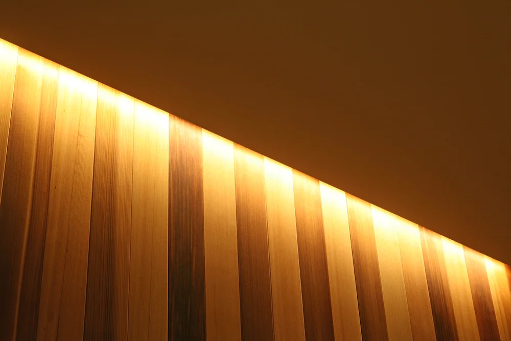 Cornice lighting along the ceiling perimeter softly illuminates the red cedar paneled walls
