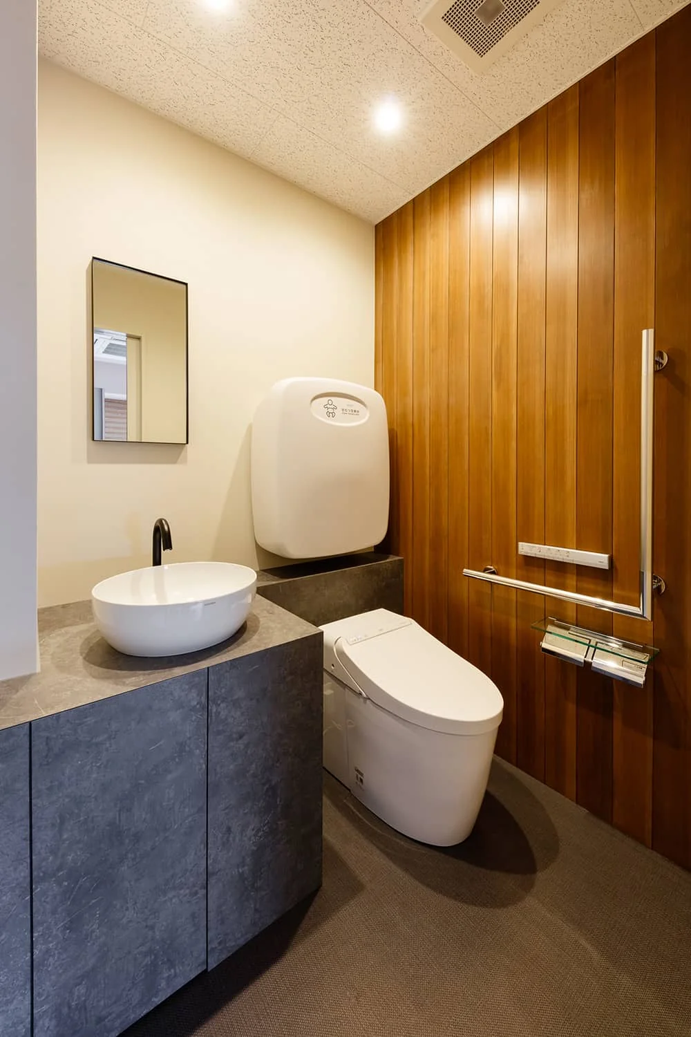 Client restroom accented with full wood paneling on one wall.