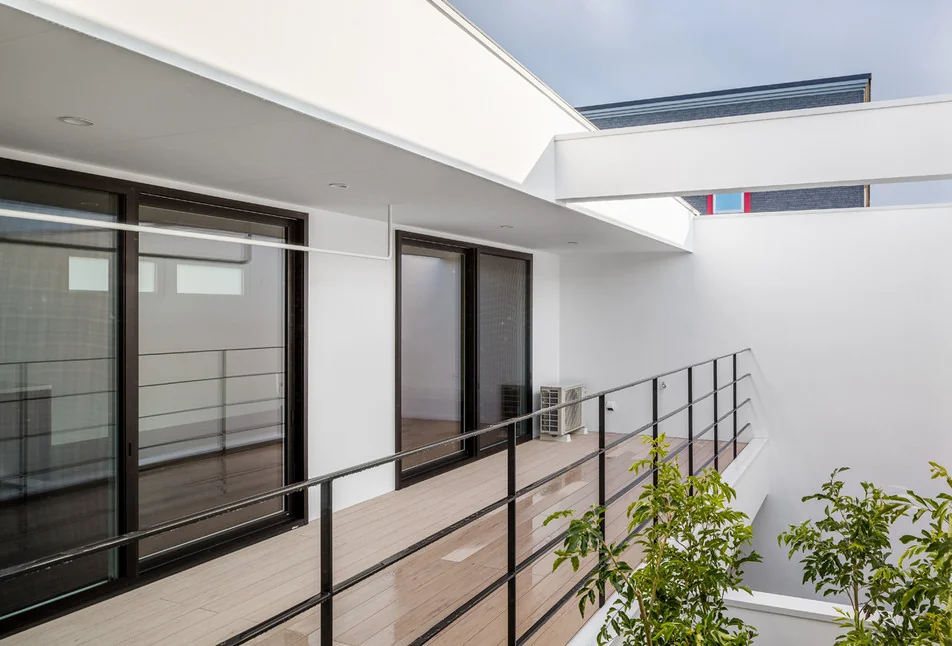 The second-floor balcony, covered by a roof, serves as a secondary living and dining area