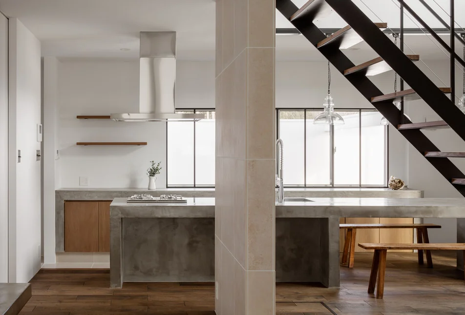 The mortar-finished kitchen and dining table impart a contemporary character to the interior space.