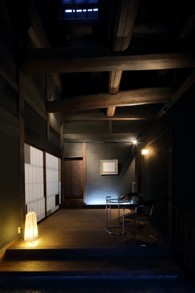 The boarded-floor room was partitioned to create an entrance hall. The black plaster absorbs the light, creating a dark, shadow-filled space.