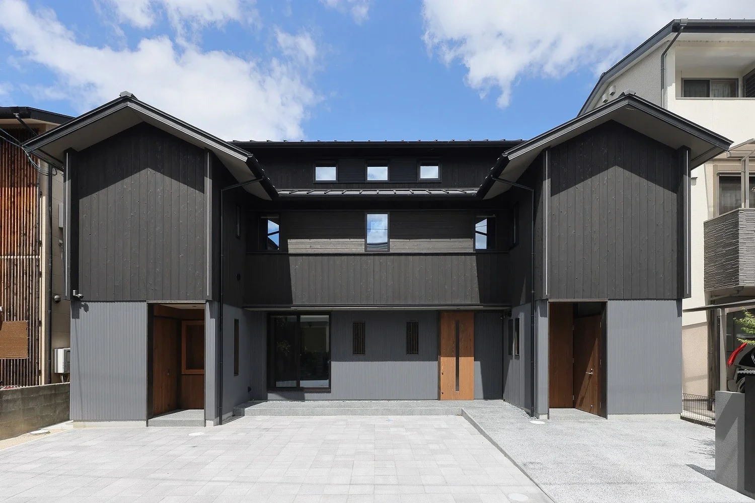 The exterior combines black charred cedar boards with corrugated steel sheets, and has three entrances corresponding to the uses of the first floor.
