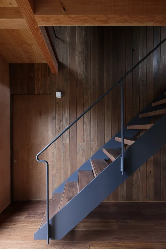 The staircase, made of thick wooden treads supported by thin steel plates and slender round steel bars, is suspended above the first-floor level.