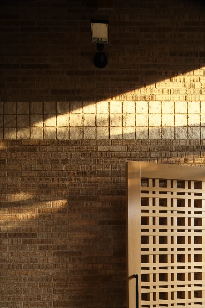 Sunlight falls diagonally across the tiled wall along the approach.