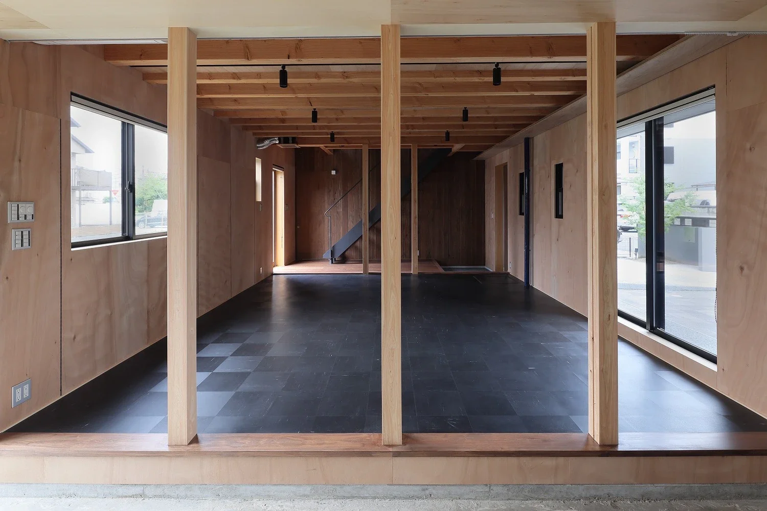 The earthen-floored space forms a continuous sequence extending to the entrance and staircase area at the back.