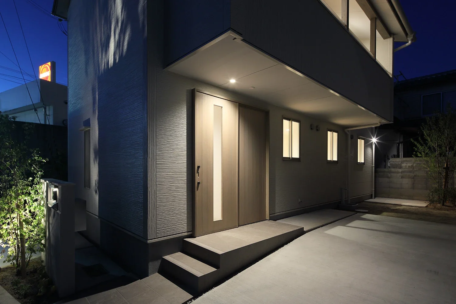The second-floor balcony serves as a canopy over the entrance and parking space.