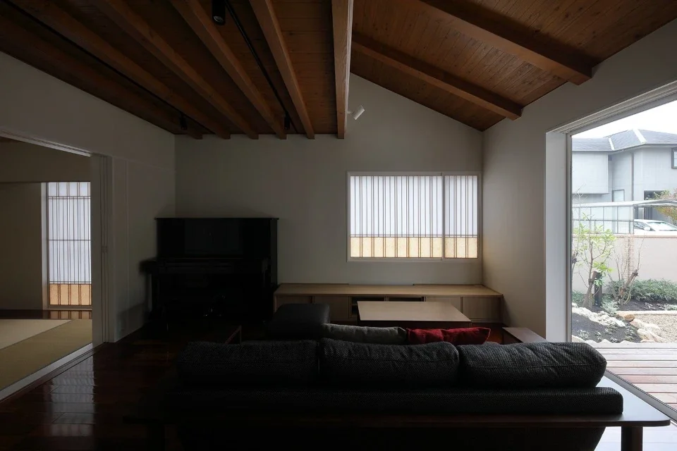 In the living room, the horizontal beams supporting the second floor intersect with the rising beams of the sloped roof.