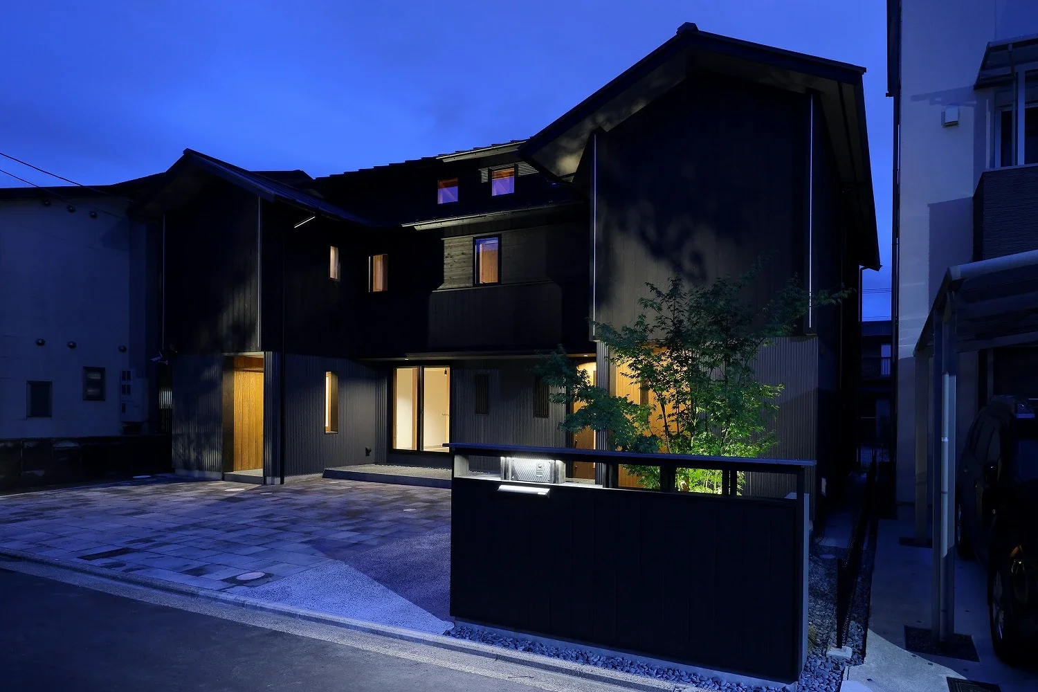 The Japanese maple behind the low wall is illuminated from its base.
