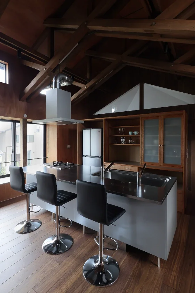 The range hood duct is also left exposed, while the kitchen cabinetry is made of the same rough plywood as the walls.