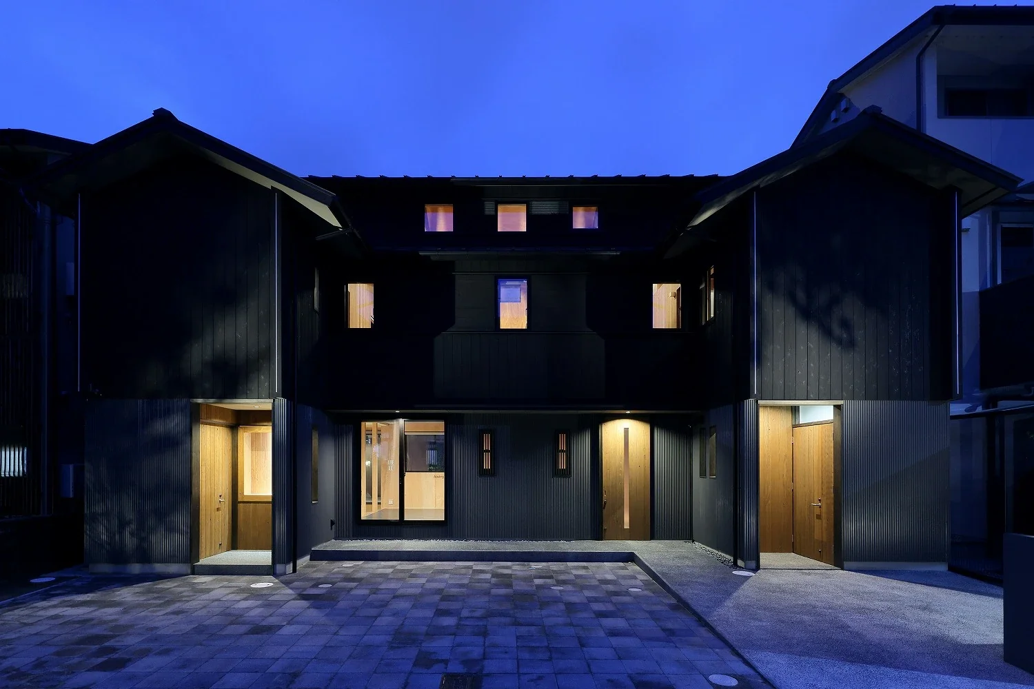 Along the street, lighting and openings are restrained to make life inside less visible.