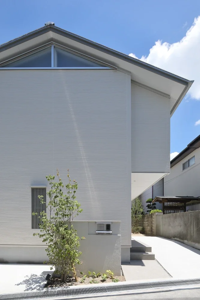 The street-facing west elevation is enclosed to block solar radiation; the kitchen’s clerestory window appears on the gable wall.