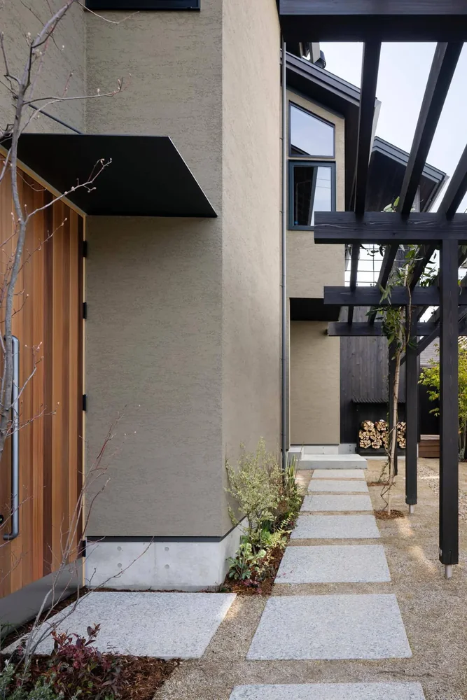 The approach features exposed aggregate concrete combined with turf grass.｜House in Toyonaka Midorigaoka
