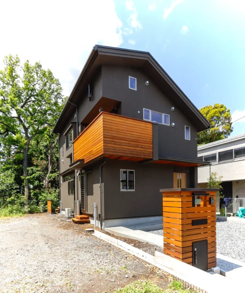 ポストの塀とバルコニーの手すりのカナダ杉板張りが外壁の黒に際立っています。