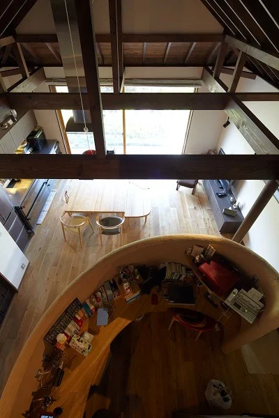 A fluid spatial composition centered around a curved wall embedded with earth from Kamakura rock｜House in North Kamakura