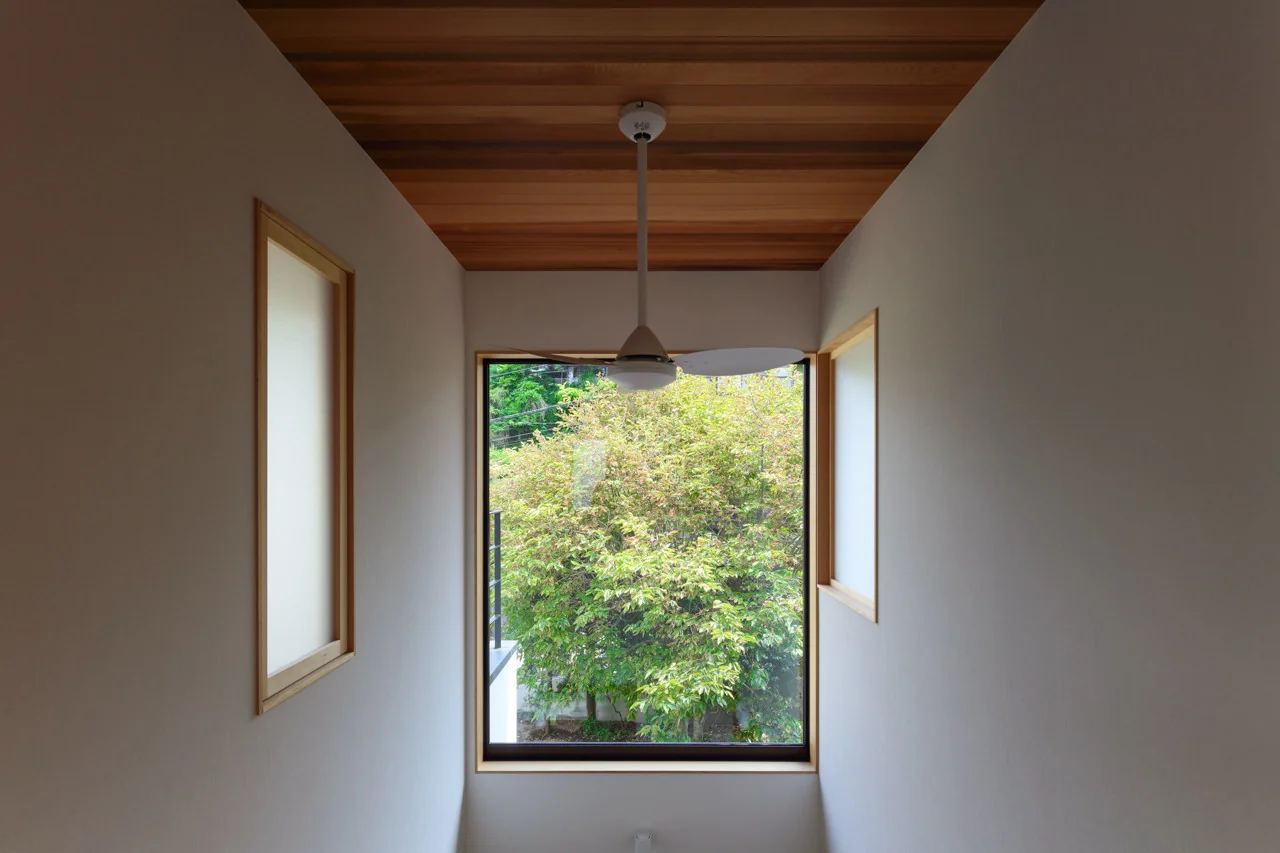 The atrium’s fixed window captures garden greenery while softly linking the upper and lower floors.