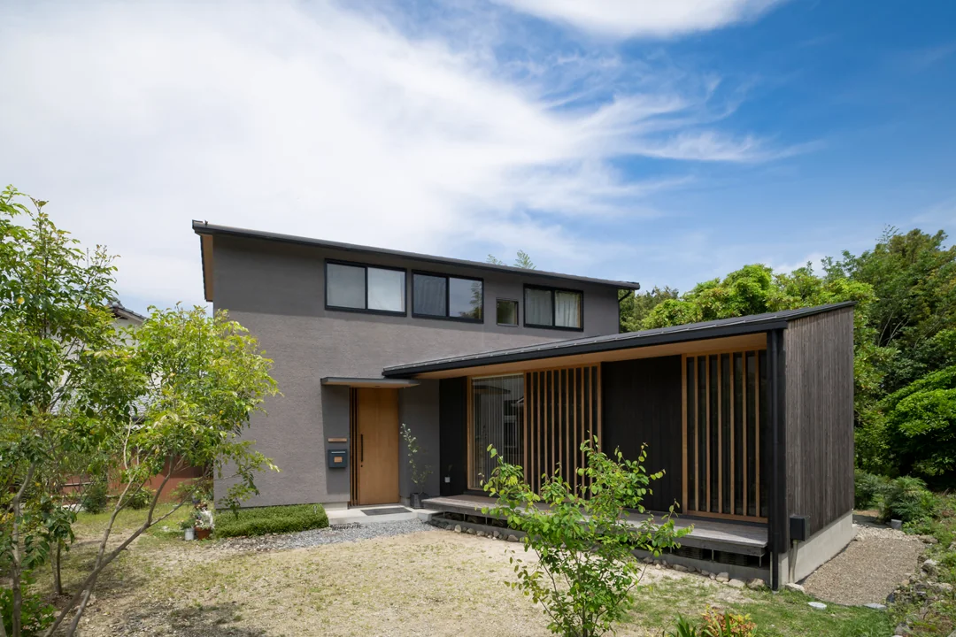 平屋と２階建てが合わさったL字型の家。外観は黒と木の色のシンプルな構成。