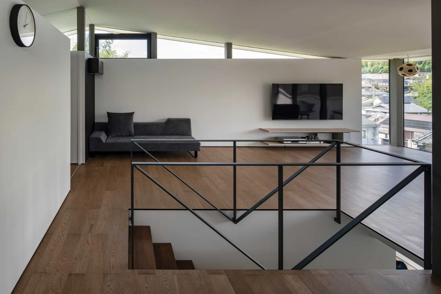 A fall-prevention balustrade and stair handrail are integrated as a continuous element crafted from steel flat bar.