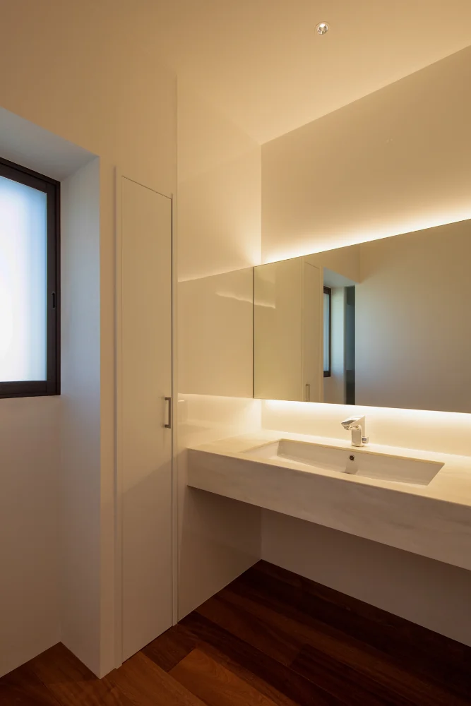 The washbasin is located at a corner of the corridor, separate from the bathroom and dressing area. The counter is the same material as the kitchen worktop.