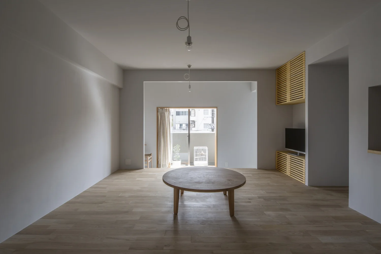 A layout in which an engawa-like veranda, study and kitchen encircle a floor-seated living room centered on a chabudai (low dining table).