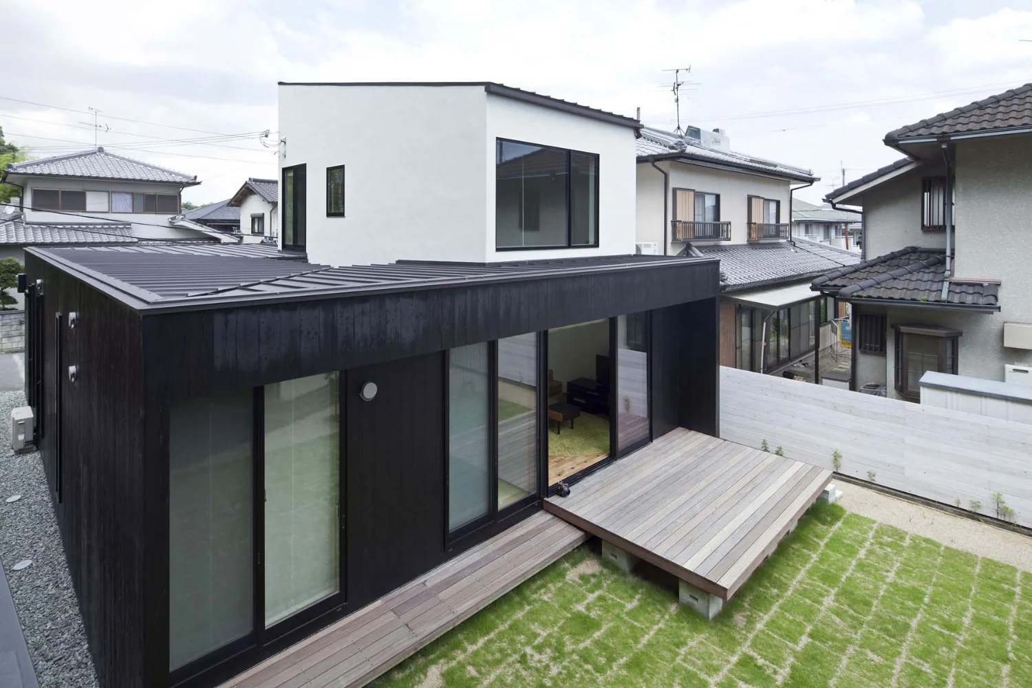 A closed black volume centered on the courtyard and a white volume opened toward the south garden.