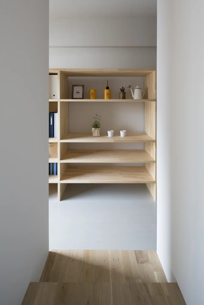 A 4.9 m-long movable furniture unit serving as both the kitchen back set and a bookshelf.｜Flat with Raised Seating Area and Through-Passage | Tranquil House
