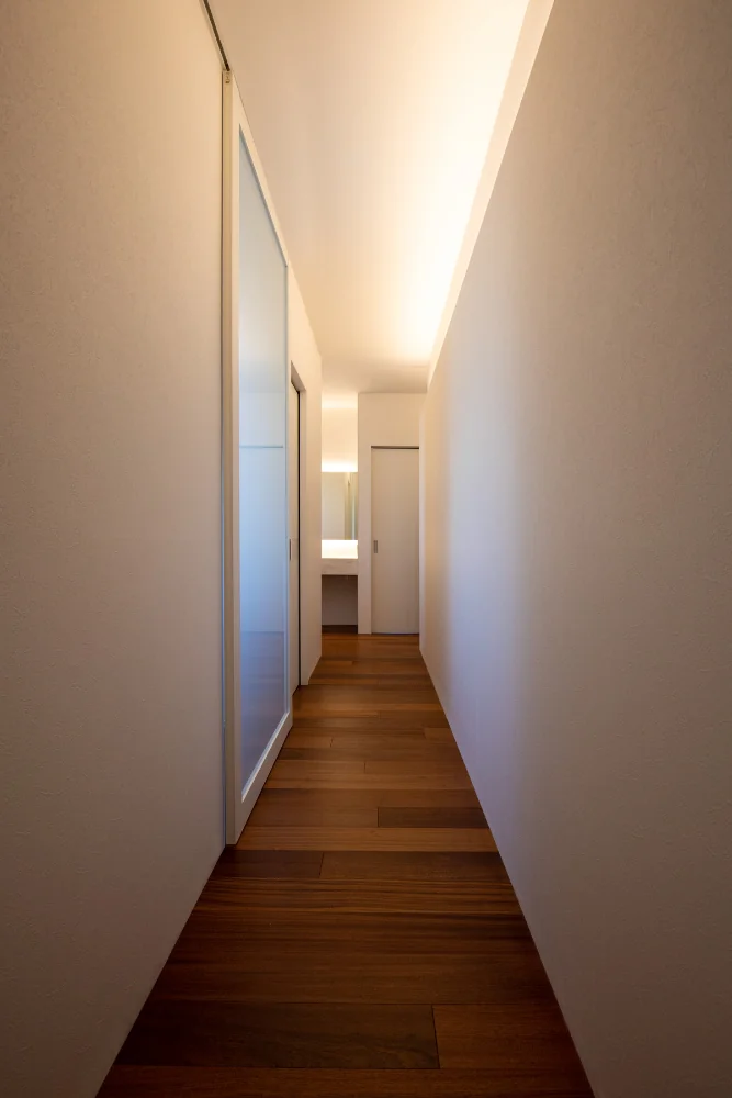 A corridor providing access to the various rooms. Indirect lighting is integrated into the wall to articulate the space.