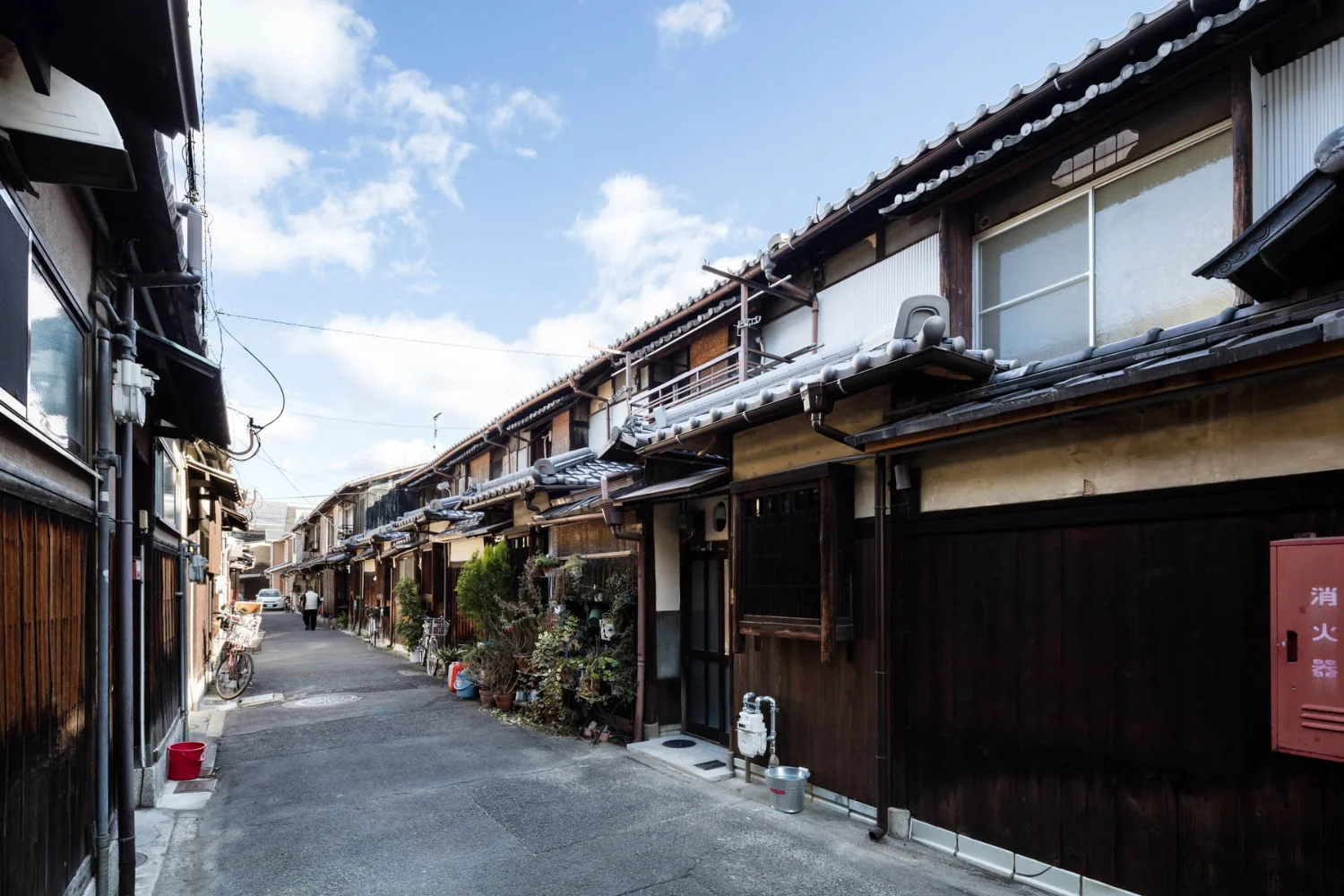 狭い道路の両側に瓦屋根の軒が連なる。戦前から続く町並み。｜戦前の賃貸向け京町家の蘇生｜昭和小路の長屋