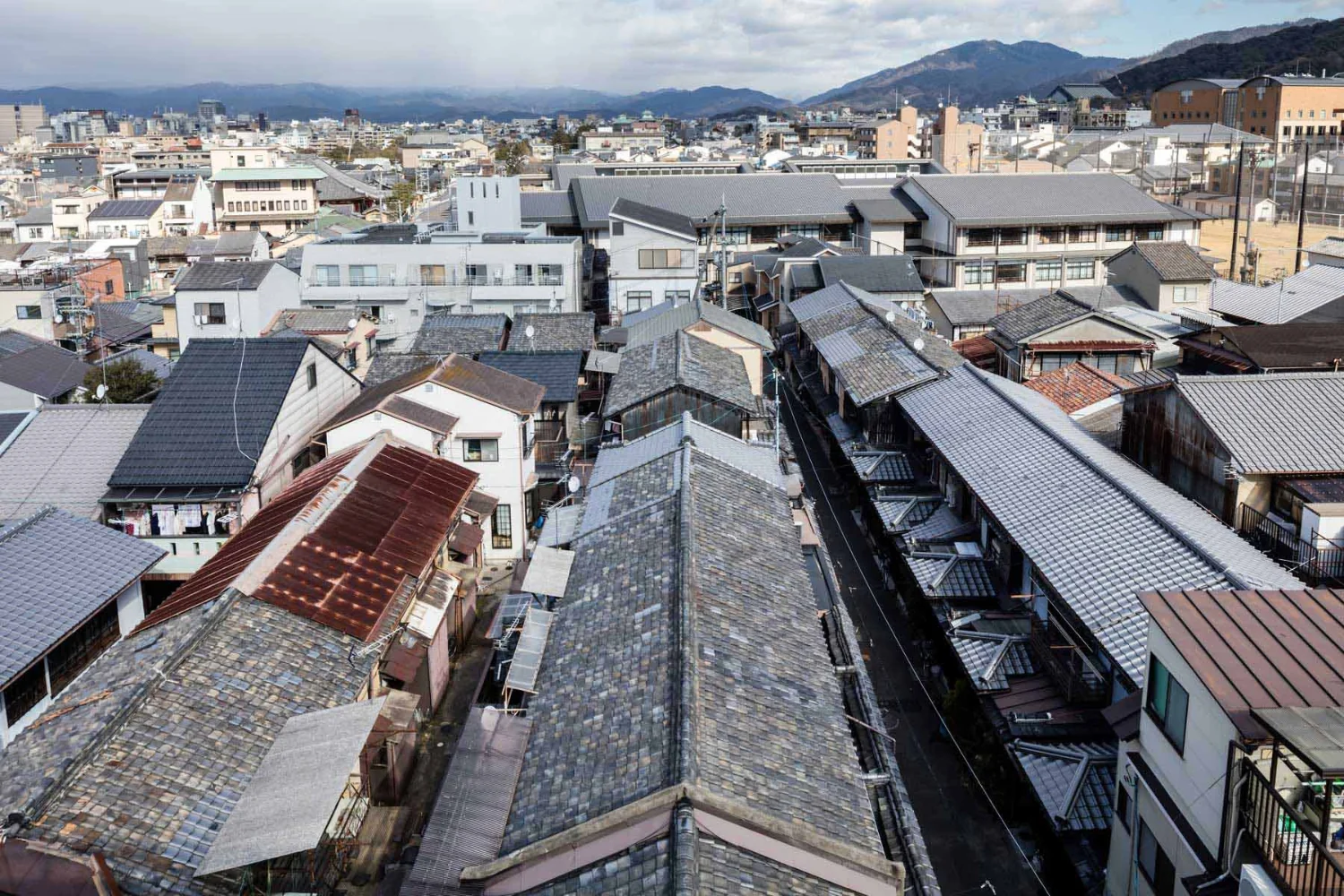 ビルと古い瓦屋根が混在する街並み。長屋の住戸を入退去のタイミングで更新していく。｜戦前の賃貸向け京町家の蘇生｜昭和小路の長屋