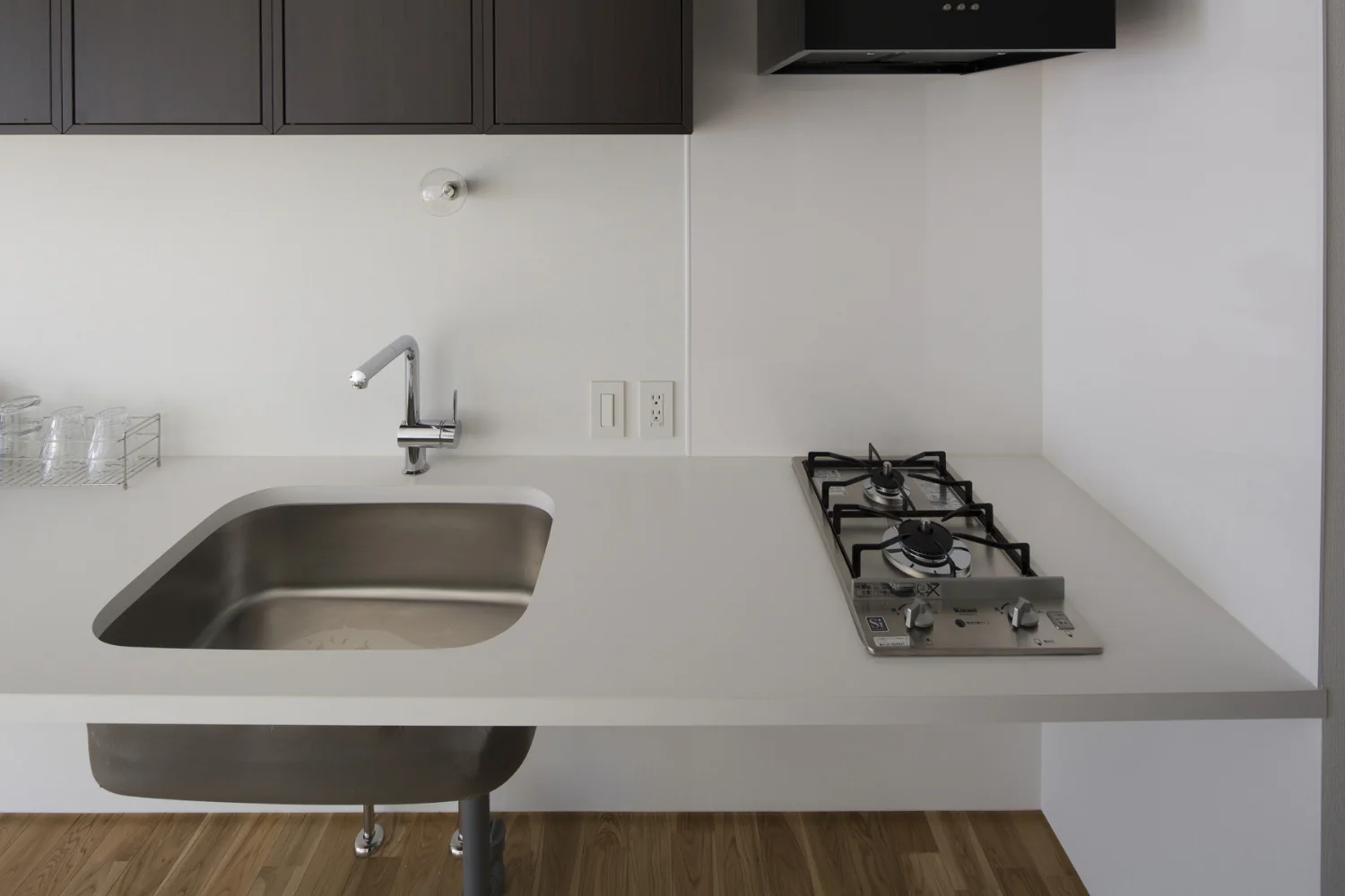 A minimalist kitchen fitted solely with a drop-in cooktop and an undermount sink.